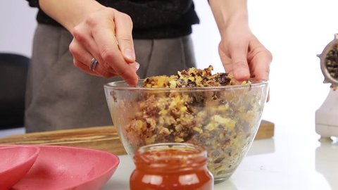 Woman adding honey to a nut butter and mixing ingredients in bowl