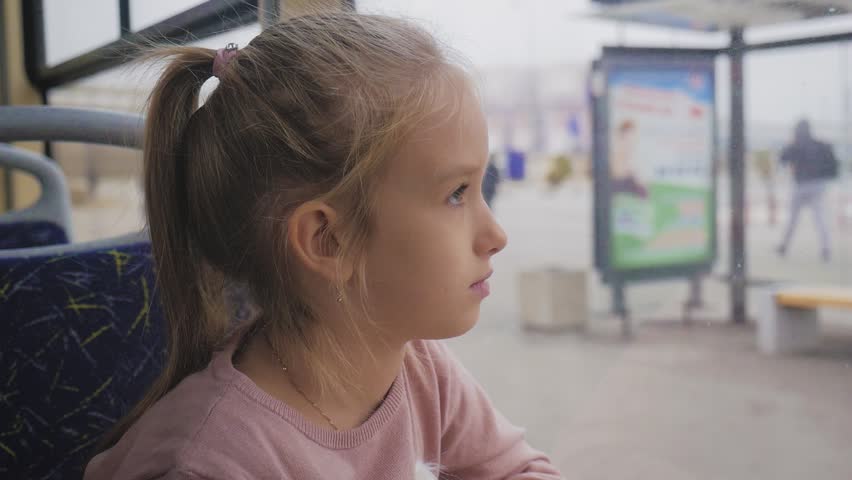 Little girl is looking through window while sitting in train.