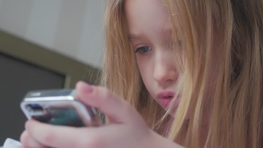 Young girl sitting on the bed and makes online shopping on a phone. Online shopping concept.
