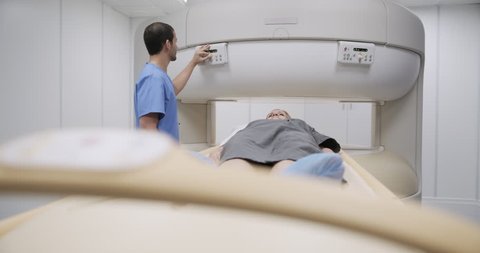 Elderly female patient with illness undergoing magnetic resonance examination. Senior woman with nurse in clinic for medical evaluation using MRI. Disease prevention using technology. Front view