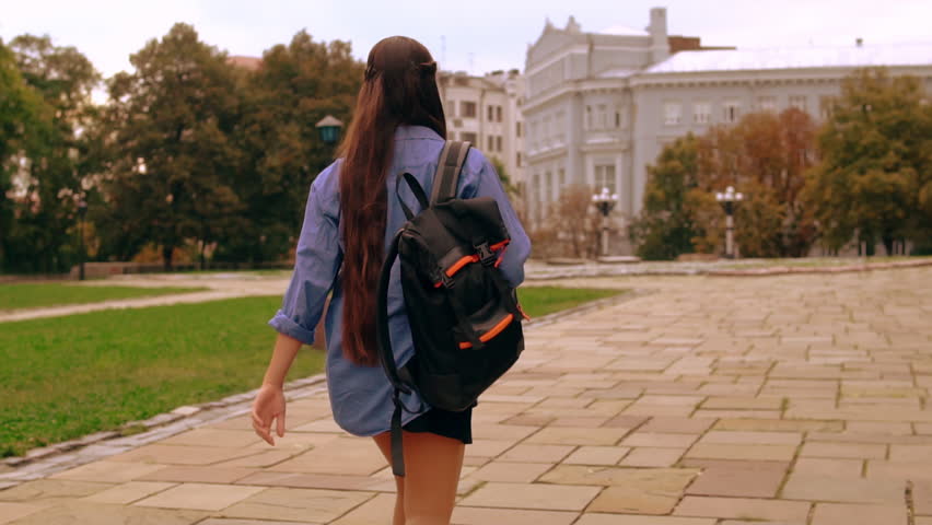 unrecognizable student strolling trendy girl with long hair wearing casual shirt and skirt walks outdoors slow motion