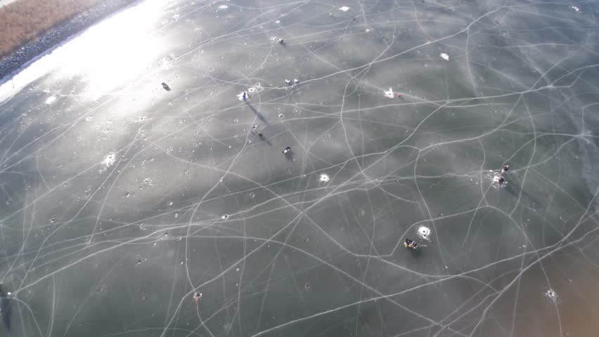 Cirlce spin pan overhead view of people ice fishing on a frozen lakeshore state park inlet lake.