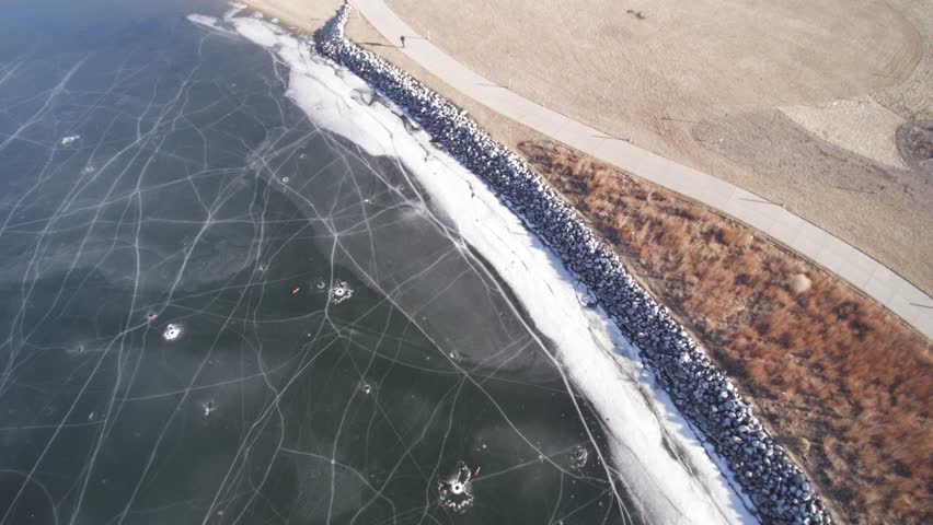 Overhead aerial view along a frozen lakeshore state park inlet lake.