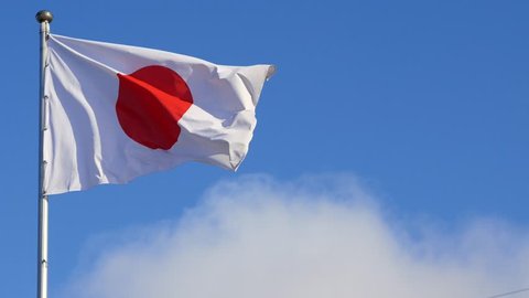 Japan flag on flagpole waving against blue sky