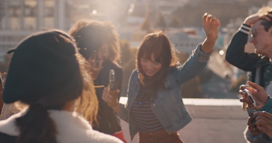 slow motion group of multiracial friends hanging out young asian woman dancing enjoying rooftop party at sunset drinking alcohol having fun on weekend celebration Royalty-Free Stock Footage #1020198643