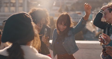 slow motion group of multiracial friends hanging out young asian woman dancing enjoying rooftop party at sunset drinking alcohol having fun on weekend celebration