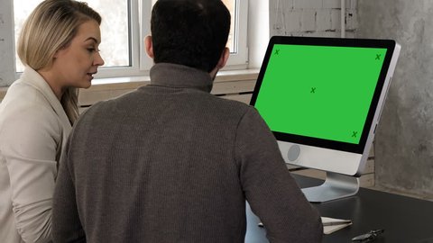 Two young businessman having a meeting at office looking in monitor. Green Screen Mock-up Display.