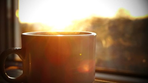 A cup of hot tea by the window at sunset. Pouring boiling water and steaming tea or coffee at dawn. Drink your morning drink.