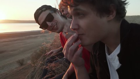 Friends smoking weed at seashore at sunset rapid slow motion
