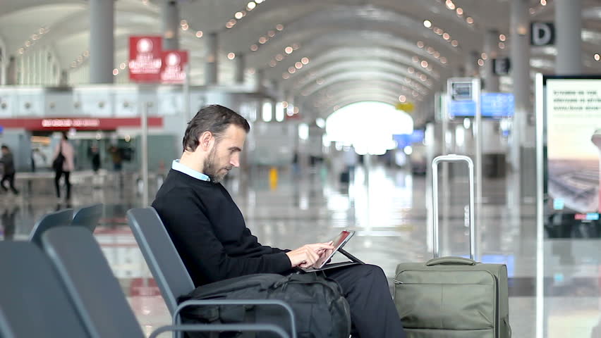 Passenger using his tablet waiting at departure lounge at the airport