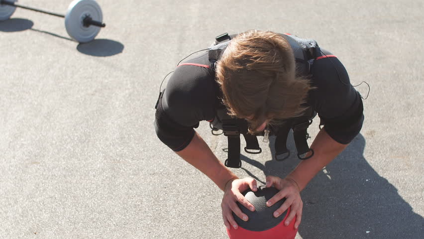 Awesome sportsman is doing exercises with a ball.