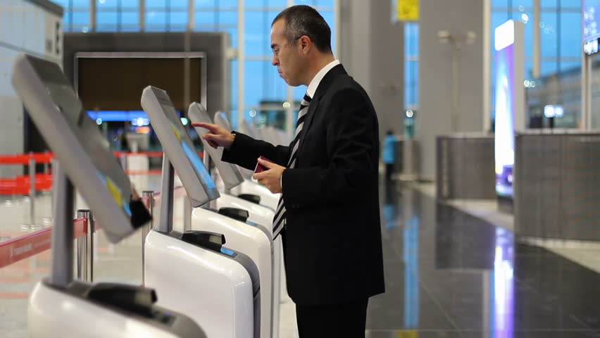 Passenger business man at the airport check in ticket at kiosk terminal
