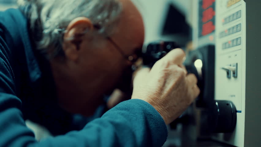 An old man checking and testing a Manual SLR camera on a machine and repairing it in his garage or repair shop