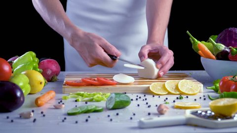 Man is cutting vegetables in the kitchen, slicing black radish