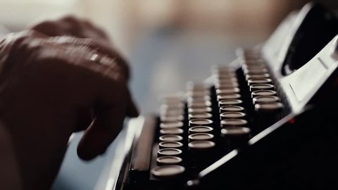 The hands of an old man are typing on an old typewriter, a writer's antique instrument, a poet or a writer composing a printed work, an old furnishings, beginning of the 20th century, handwriting