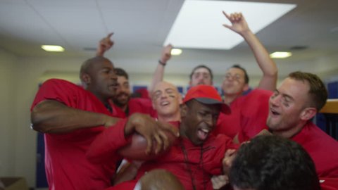 4K Excited American football team celebrate a victory by lifting their coach in the air Stock Video