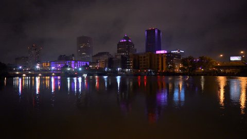 The Rochester New York city skyline is reflected in the smooth water after sunset