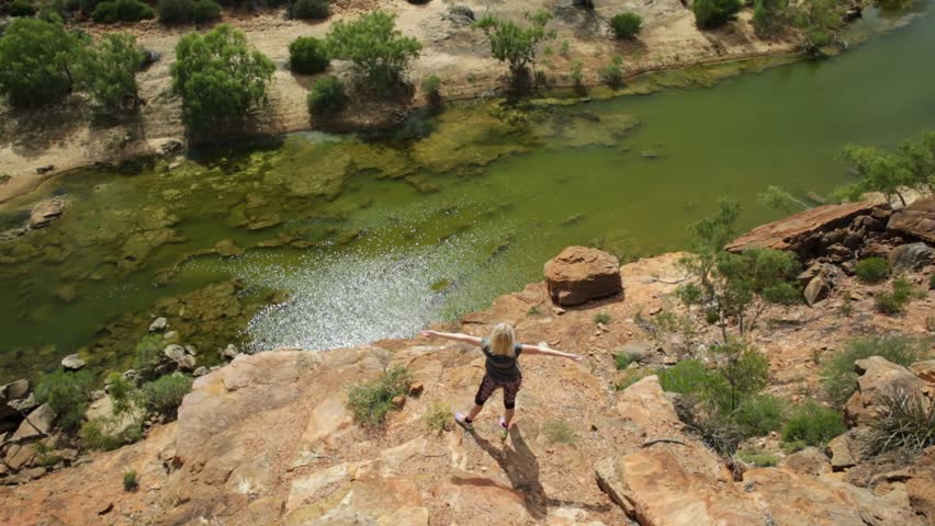 Blonde caucasian woman with open arms enjoys in the lower part of Murchison River in Kalbarri National Park, Western Australia. Happy freedom travel in the outback of Australia. Sunny in summer