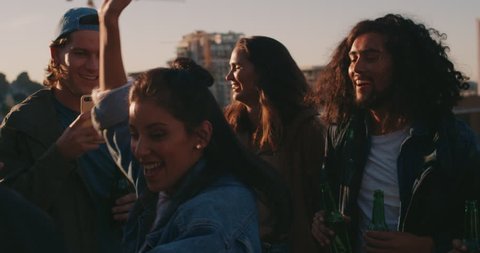 mixed race woman dancing group of diverse friends hanging out enjoying rooftop party dance music at sunset drinking alcohol having fun on weekend gathering