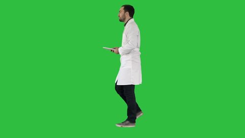 Doctor using tab while walking on a Green Screen, Chroma Key.