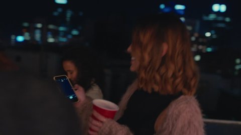 group of multiracial friends dancing on rooftop party at night beautiful young woman taking photos using smartphone sharing wild weekend lifestyle on social media
