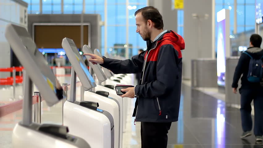 Passenger Checking In At Airport With Kiosk And Printing Boarding Pass