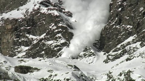 Snow avalanche in the mountains. Alps snow falling from high hills. 
