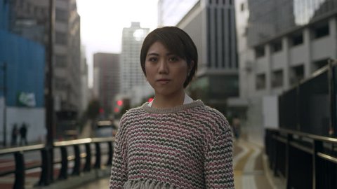 Portrait of Japanese woman standing in the middle of a quiet sidewalk in a metropolitan city in Japan with soft natural lighting. Medium shot on 4k RED camera. 