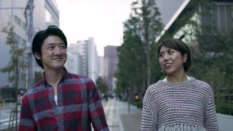 Cheerful happy Japanese couple walking down a quiet metropolitan street. 4k RED camera. ஸ்டாக் வீடியோ