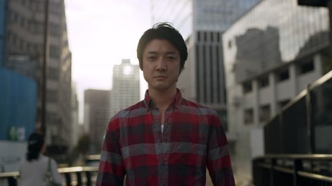 Portrait of Japanese man standing in the middle of a sidewalk in a metropolitan city in Japan with soft natural lighting. Medium shot on 4k RED camera.