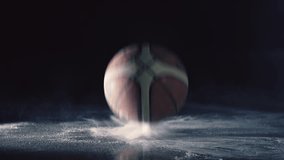 A basketball bouncing in super slow motion on chalk powder leaving white dust behind it giving it a cool effect. The scene has a dark background but the area is spotlit focusing on the ball. - Powered by Shutterstock - Get 15% off with code: PIKWIZARD15