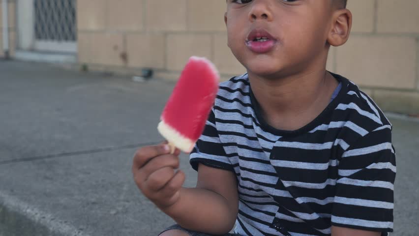 Face shot of an inocent African American kid eating ice-cream wide shot