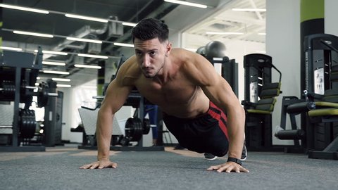 Caucasian man with naked torso doing push ups during training in the gym. Dolly shot.