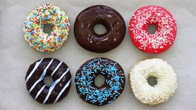 Donuts of different colors on cardboard, top view, stop motion animation. Full HD - Powered by Shutterstock - Get 15% off with code: PIKWIZARD15