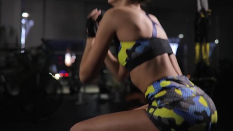 Beautiful woman exercising in gym, squat with weight in military sporty costume