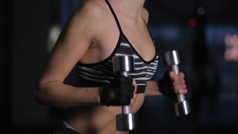 Beautiful woman lifting dumbbell for bicep in gym