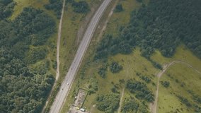 Aerial view of the road with moving cars. Clip. Road through the fields and forest