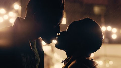 young african american couple kissing in rain holding hands enjoying romantic connection on beautiful rooftop at night sexy cinematic kiss in 4k making out on roof