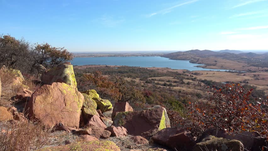 View of beautiful landscape with lake and autumn colors of wild growing trees and brush. View from Wichita Mountains.