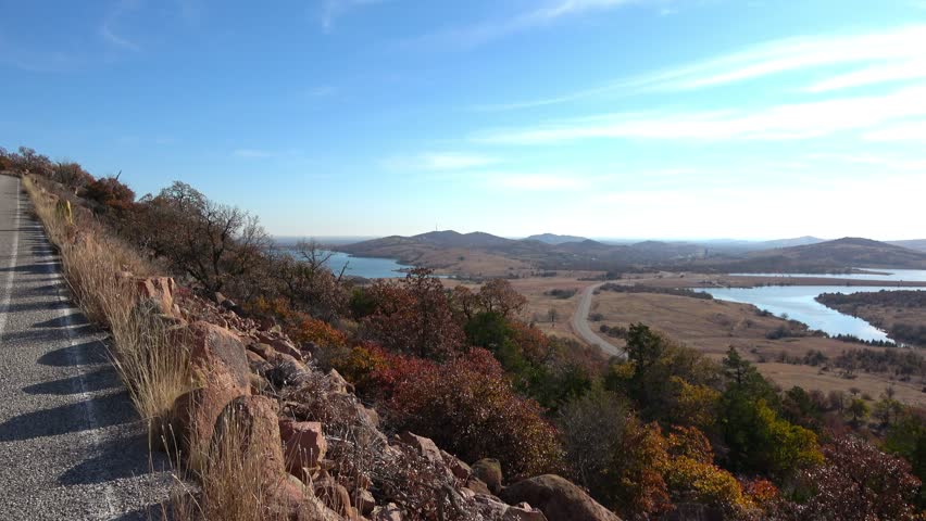 View of beautiful landscape with lake and autumn colors of wild growing trees and brush. View from Wichita Mountains.