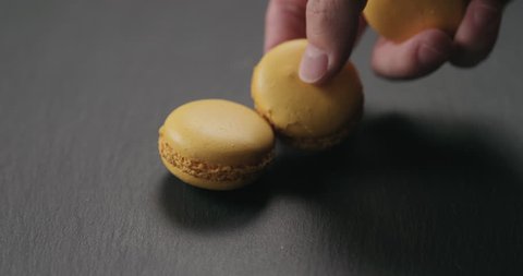 Slow motion closeup man hand put orange macarons on slate board