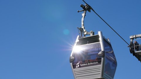 BARCELONA, SPAIN - AUGUST 15, 2018: Montjuic Cable Car transportation system at Barcelona, low angle shot of gondola passing by against clear blue sky. Unidentified people seen inside closed cabin
