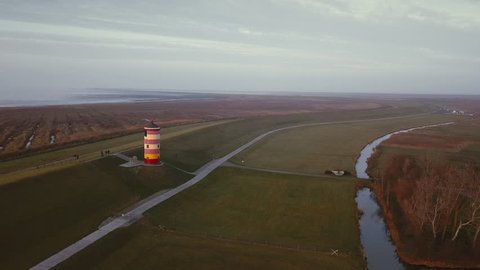 Lighthouse on the North Sea in Germany. Lighthouse on top of hill in beautiful sunset light on the german holiday. Lighthouse in Friesland