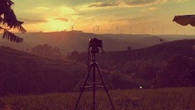 Camera on sunset and Windmill or wind turbine on sunset on mountain golden sky and cloud beauty,