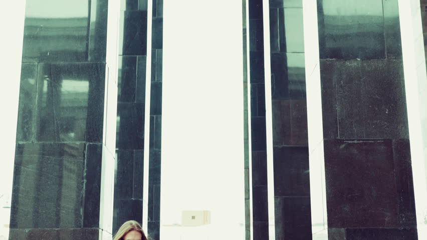 Portrait of attractive bearded hipster man in red fashion coat. Thoughtful and resolute look in big town. Modern businessman model with long hair. Slow motion. Walking