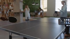 young business people playing ping pong in office enjoying competitive fun colleague using smartphone sharing game on social media