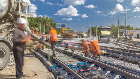 Pouring ready-mixed concrete after placing steel reinforcement to make the road by concrete mixer timelapse. Reconstruction of tram tracks