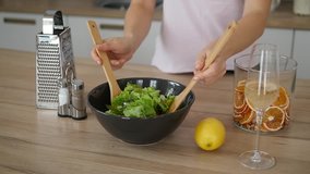 Woman prepares salad in home kitchen.