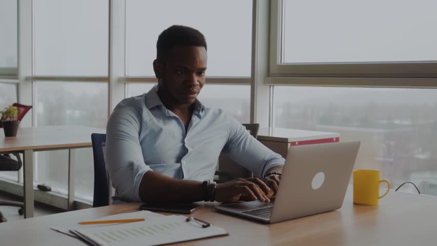 Young afro american business professional working on a lap top. Solving serious issues. Project work. Office routine Royalty-Free Stock Footage #1020349678