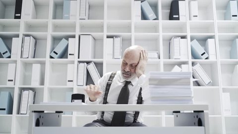 Lazy office worker doing a repetitive dull job, he is stamping a pile of paperwork